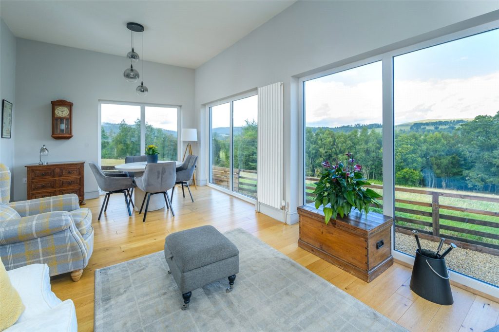 The living and dining room with large windows overlooking the countryside